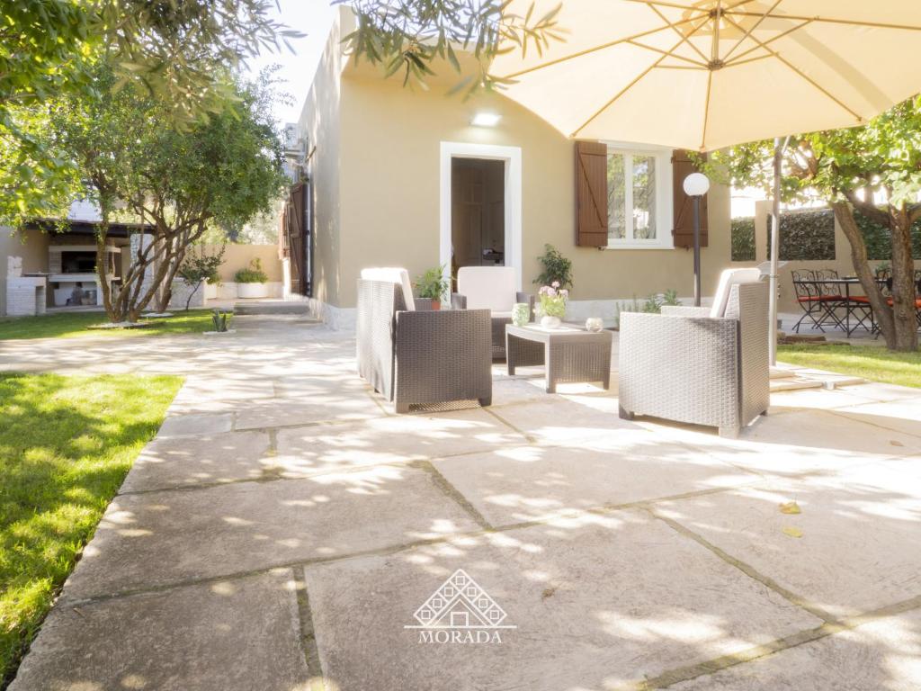 patio con sedie e ombrellone di fronte a casa di Villa Laura - MORADA a SantʼAndrea