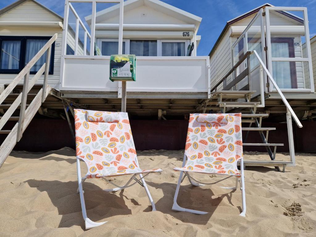dos sillas sentadas en la arena frente a una casa en Slaapstrandhuisje Sleeping Beach House 676 Dishoek aan Zee en Dishoek