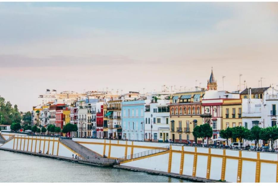 un grupo de edificios junto a un río con un puente en HABITACION INDIVIDUAL, en Sevilla