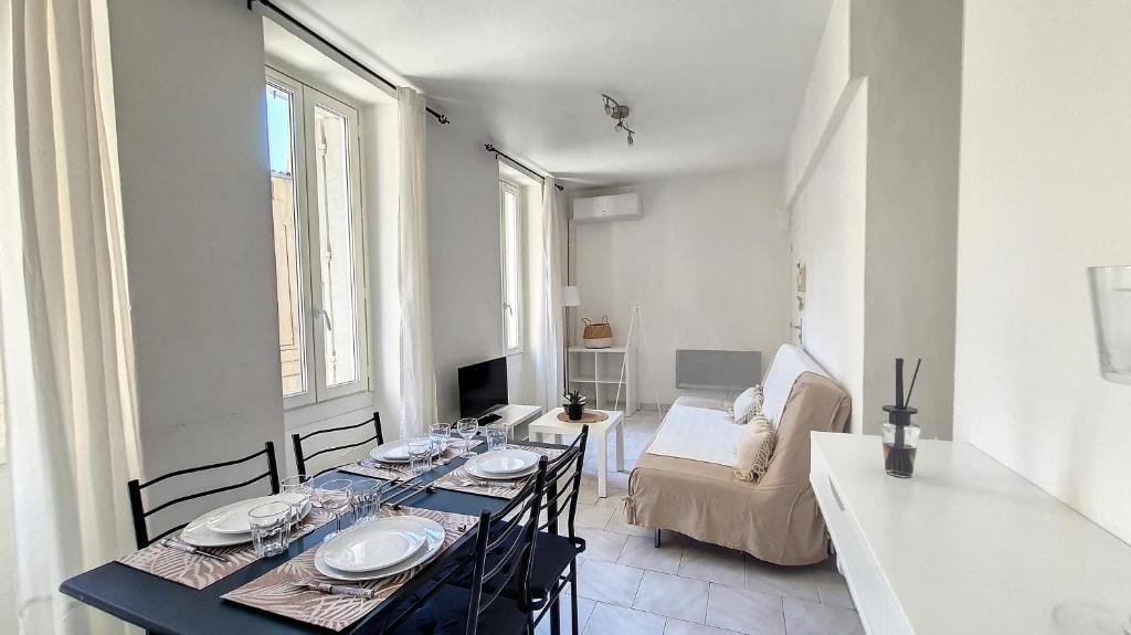 un salon avec une table, des chaises et un canapé dans l'établissement Appartement lumineux, climatisé, cœur de ville., à Avignon