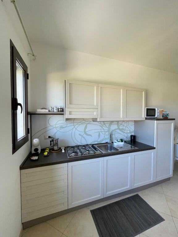 eine Küche mit weißen Schränken und einer schwarzen Arbeitsplatte in der Unterkunft Mondoverde Apartments & Rooms in Surano