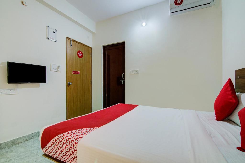 a bedroom with a white bed with red pillows at Varcity Comforts Near Ragigudda Sri Prasanna Anjaneyaswamy Temple in Bangalore