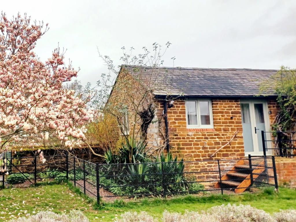 uma casa de tijolos com uma árvore florida no quintal em Stowe Fields em Northampton
