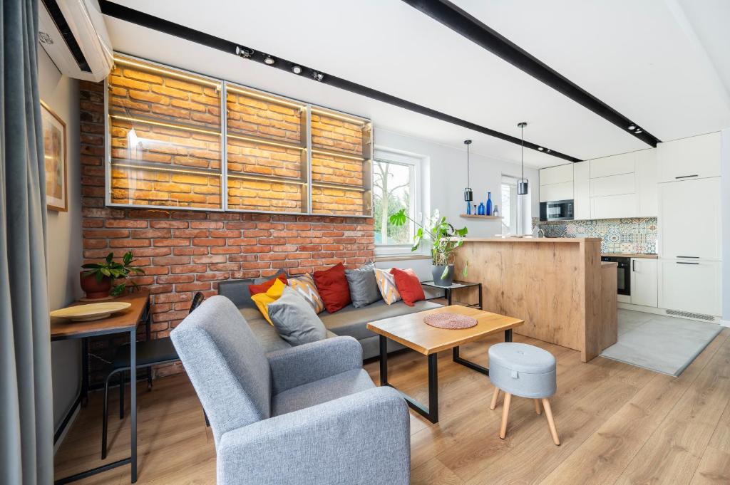 a living room with a couch and a brick wall at Rudzka Góra Comfy Apartment in Łódź