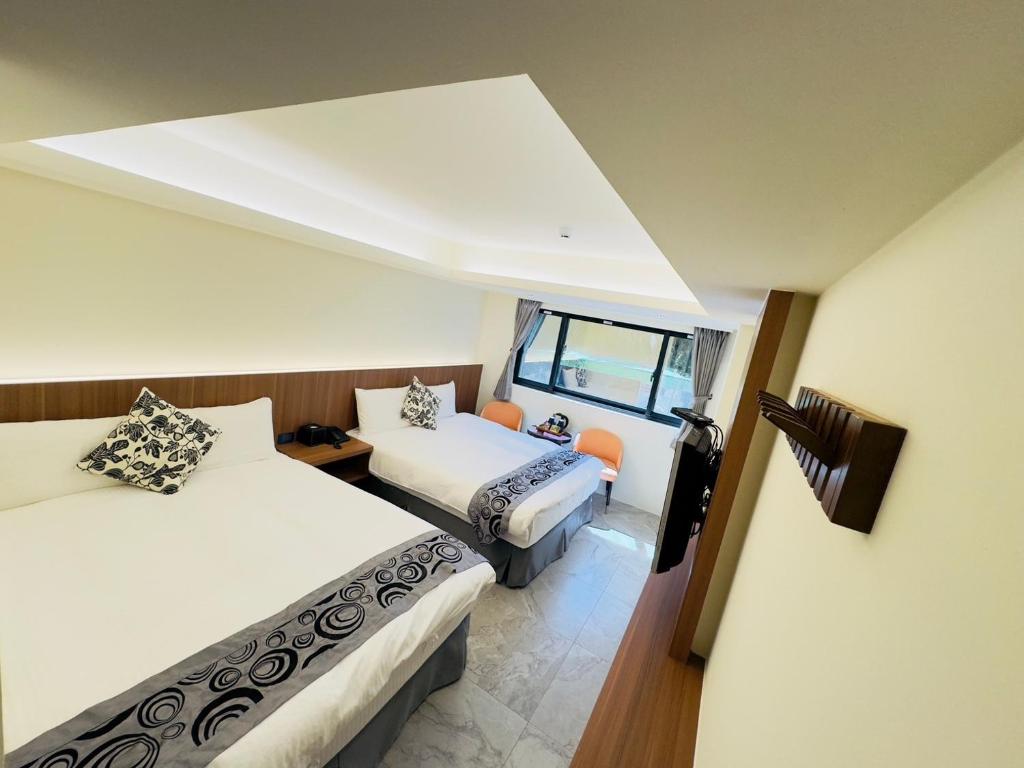 a hotel room with two beds and a window at Dafong Hotel in Zhongzheng