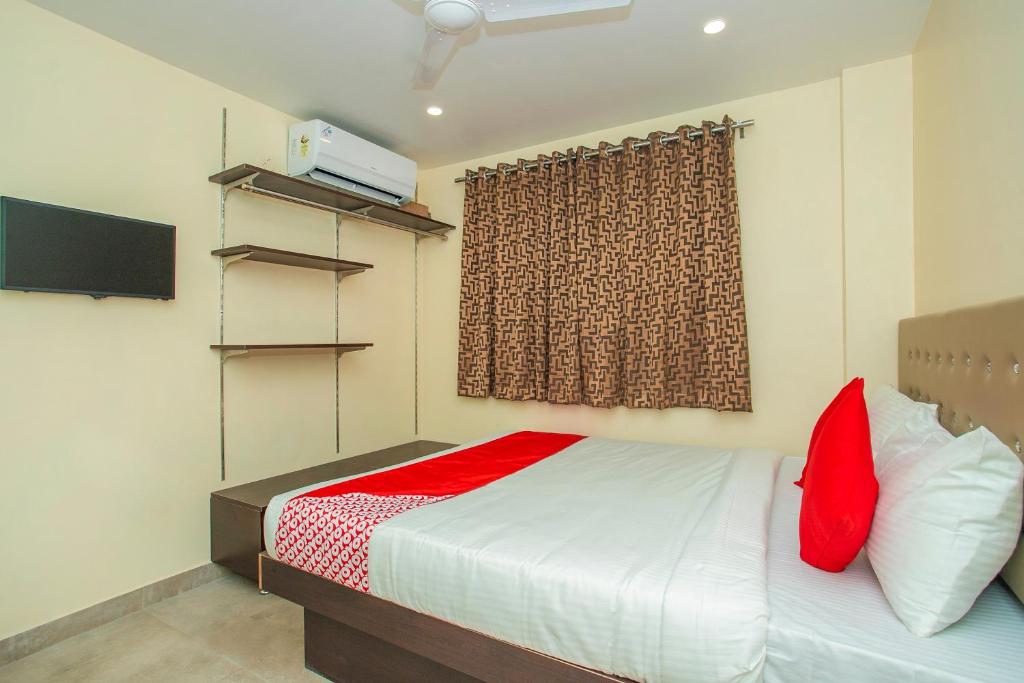 a bedroom with a bed with red pillows and a window at Super OYO Flagship Olivia Comforts Near Nexus Mall Koramangala in Bangalore