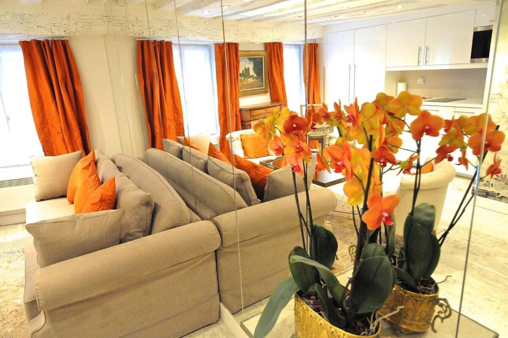 una sala de estar con 2 sofás y cortinas naranjas. en Tenderness at Notre Dame, DELACROIX, en París