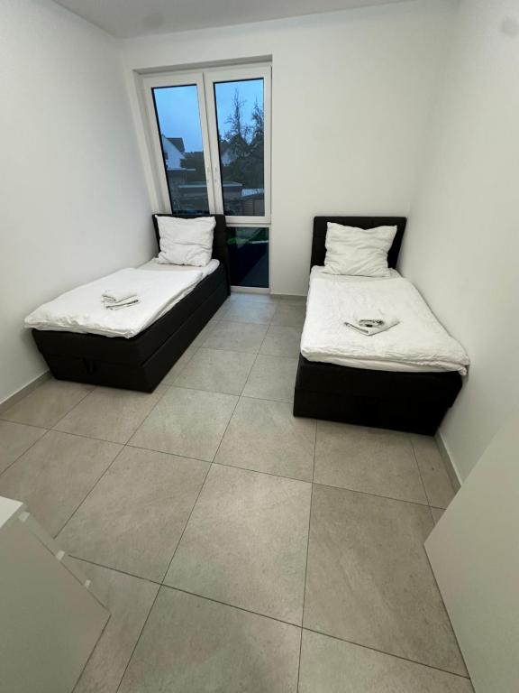 two beds in a room with a tile floor at 4 ZKB Neubauwohnung mit Stil in Bielefeld