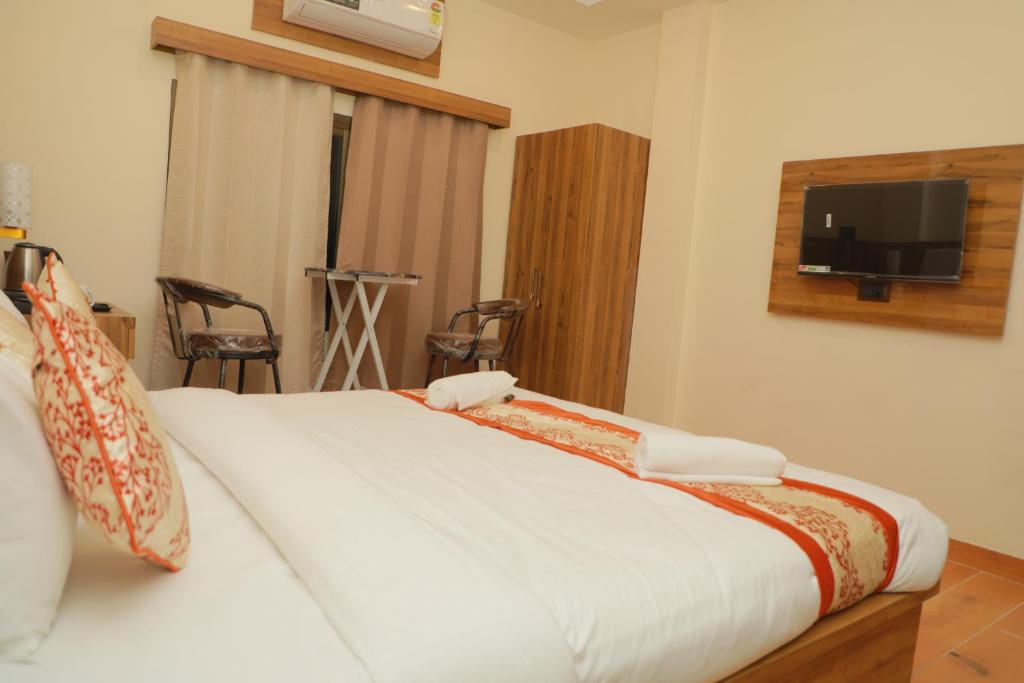 um quarto com uma cama e uma televisão na parede em De Classico Hotel em Varanasi