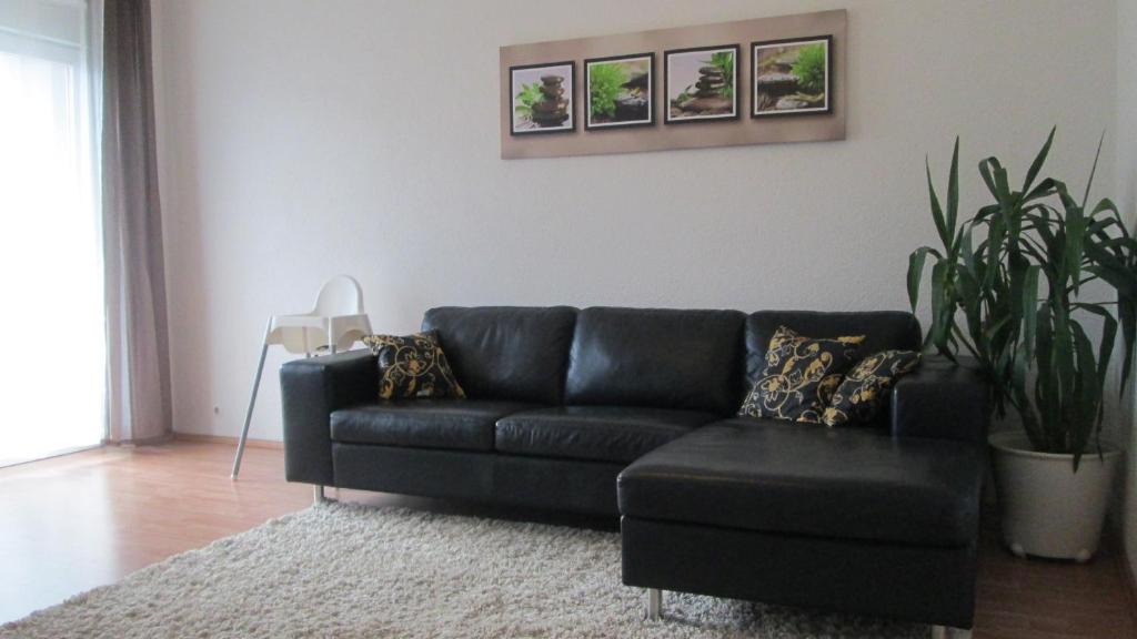 a black couch in a living room with a plant at Sweet Home in Friedrichshafen