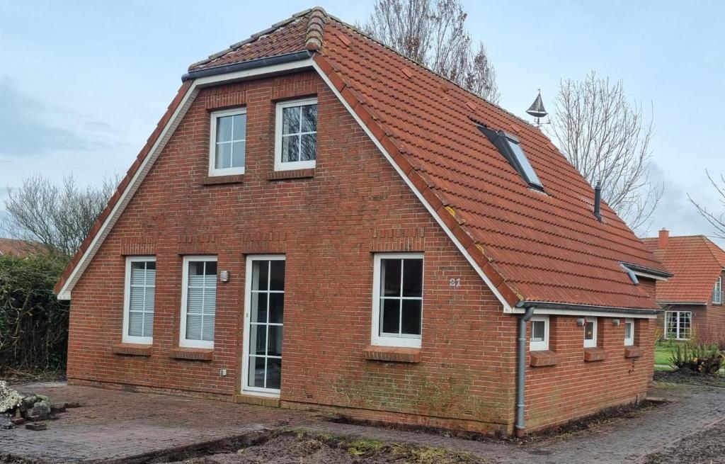 an old brick house with a red roof at Ferienhaus Pfeffermuschel in Neßmersiel