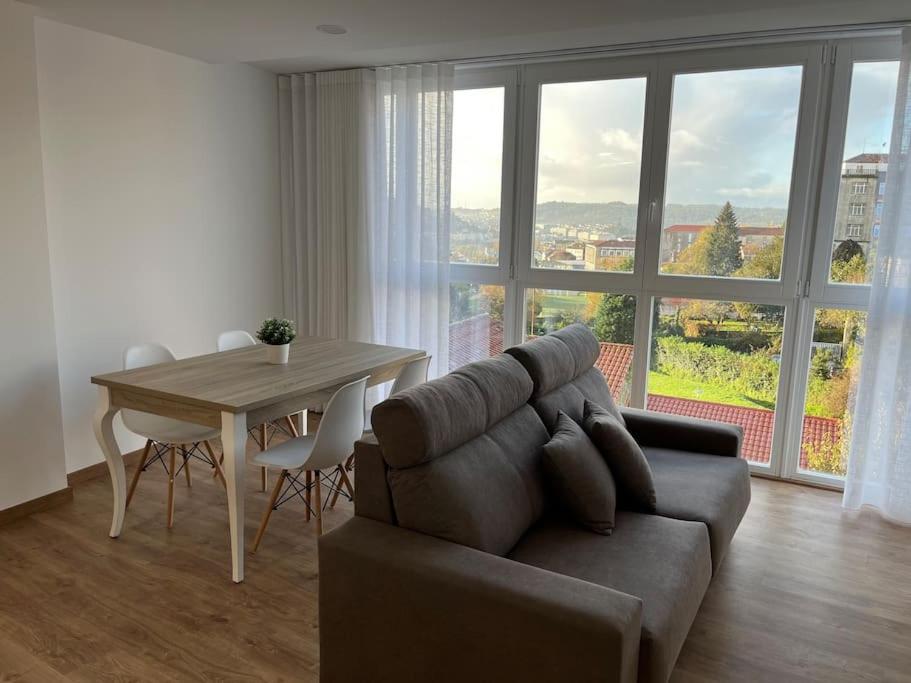 ein Wohnzimmer mit einem Sofa und einem Tisch in der Unterkunft Apartamento céntrico con vistas in Santiago de Compostela