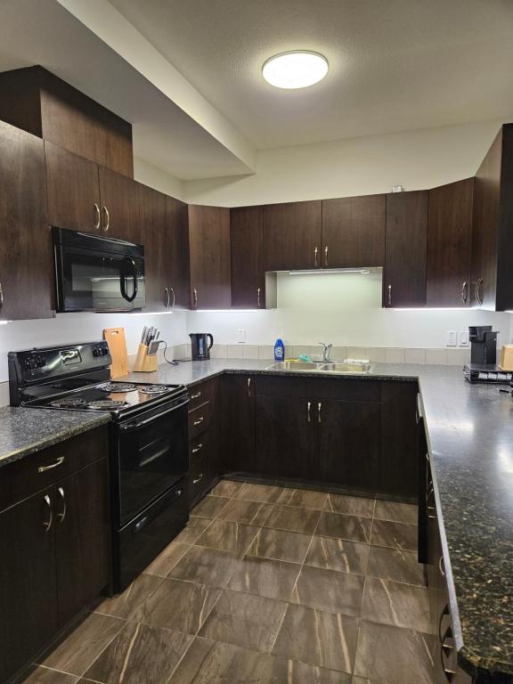 a kitchen with wooden cabinets and black appliances at SureStay Studio by Best Western Hardisty in Hardisty