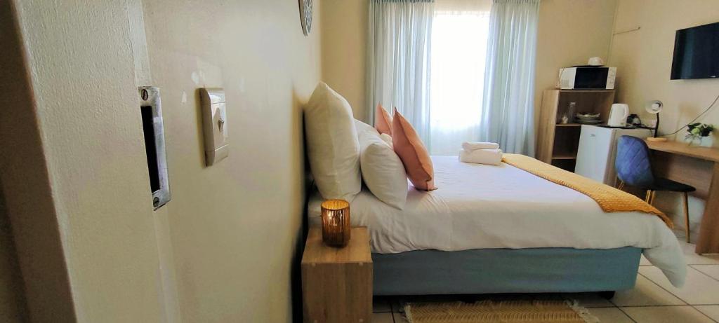 sypialnia z łóżkiem z poduszkami i oknem w obiekcie Nkulies Nest w mieście Centurion