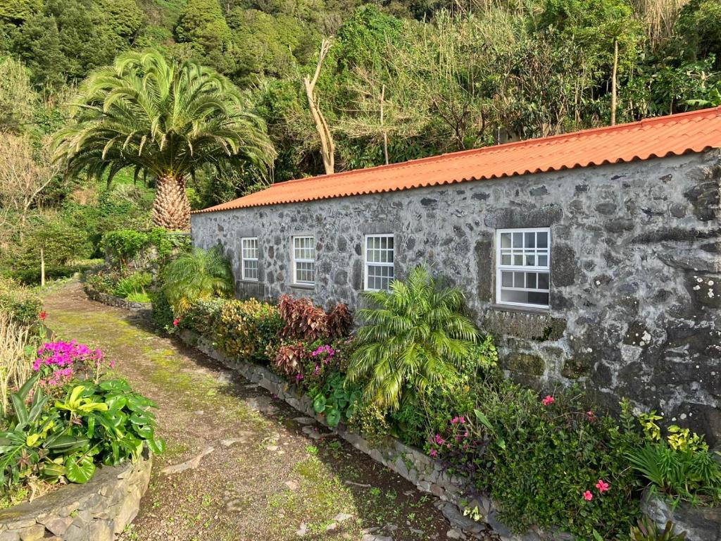 un edificio de piedra con plantas y flores delante de él en Vistalinda Farmhouse en Fajã dos Vimes