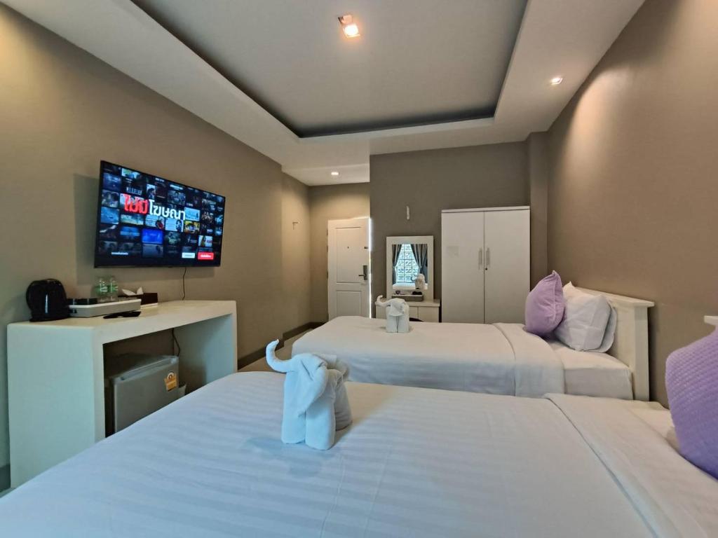 a hotel room with two beds and a flat screen tv at The Guest Chang Moi Hotel in Chiang Mai