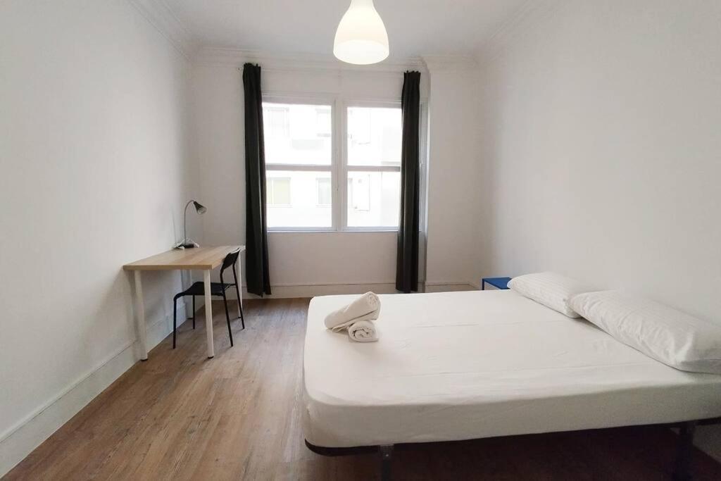 Schlafzimmer mit einem Bett, einem Schreibtisch und einem Fenster in der Unterkunft VibesCoruña- Ferrocarril 2 in A Coruña