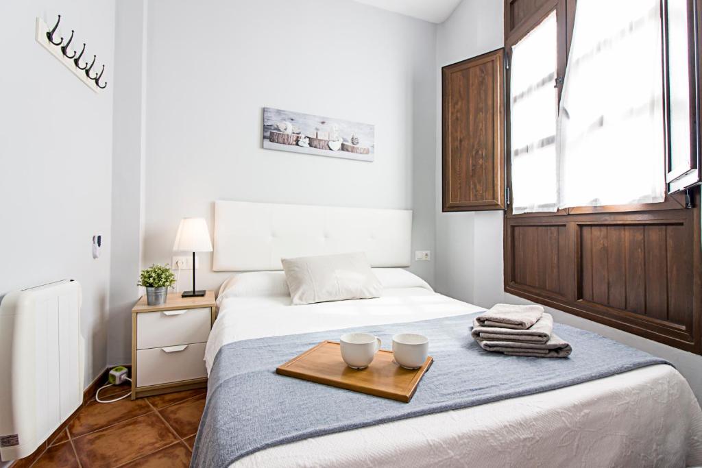1 dormitorio con 1 cama con 2 tazas en una bandeja en Granada FreshApartments by Bossh! Apartments, en Málaga