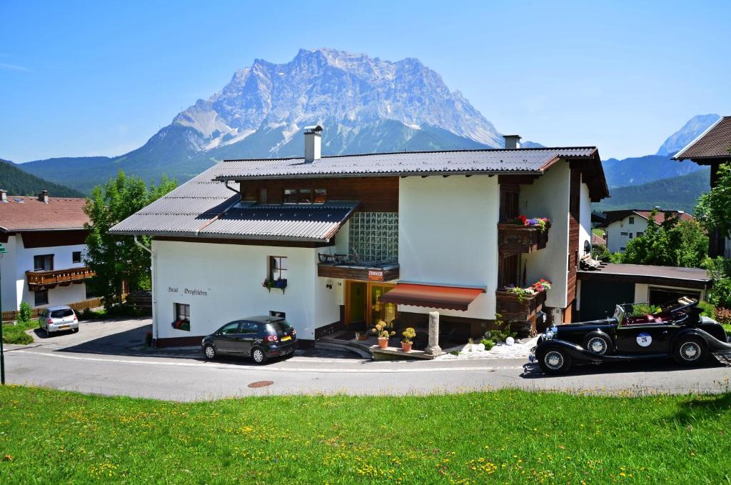 ein Haus mit einem Auto davor geparkt mit einem Berg in der Unterkunft Haus Bergfrieden in Lermoos