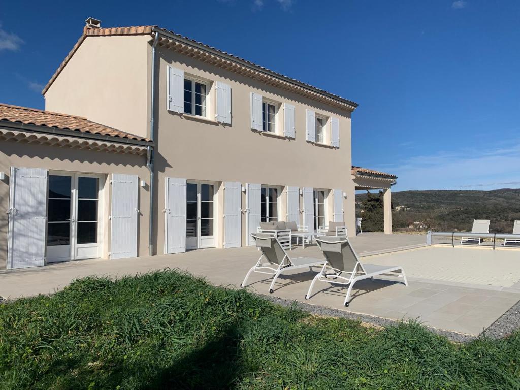 a house with two chairs and a table in front of it at Les Collines de Saint-André in Saint-André-de-Cruzières
