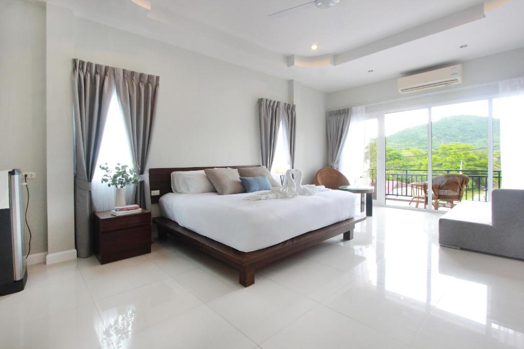 a bedroom with a bed and a balcony at The Langstan Suites in Nai Harn Beach