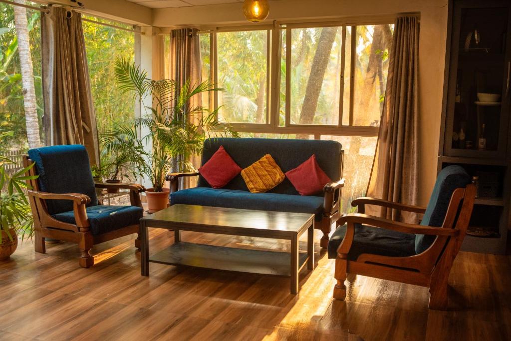uma sala de estar com um sofá e duas cadeiras e uma mesa em Tranquil Homestay em Mangalore