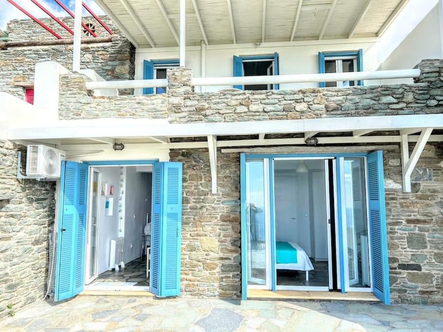 a stone house with blue doors and a balcony at Aggeliki's Cycladic Villa by Hostandros in Batsi