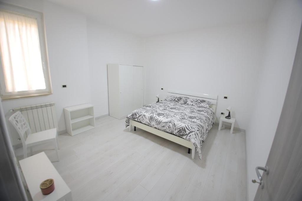 a white bedroom with a bed and a window at Il nascondiglio in San Ferdinando di Puglia