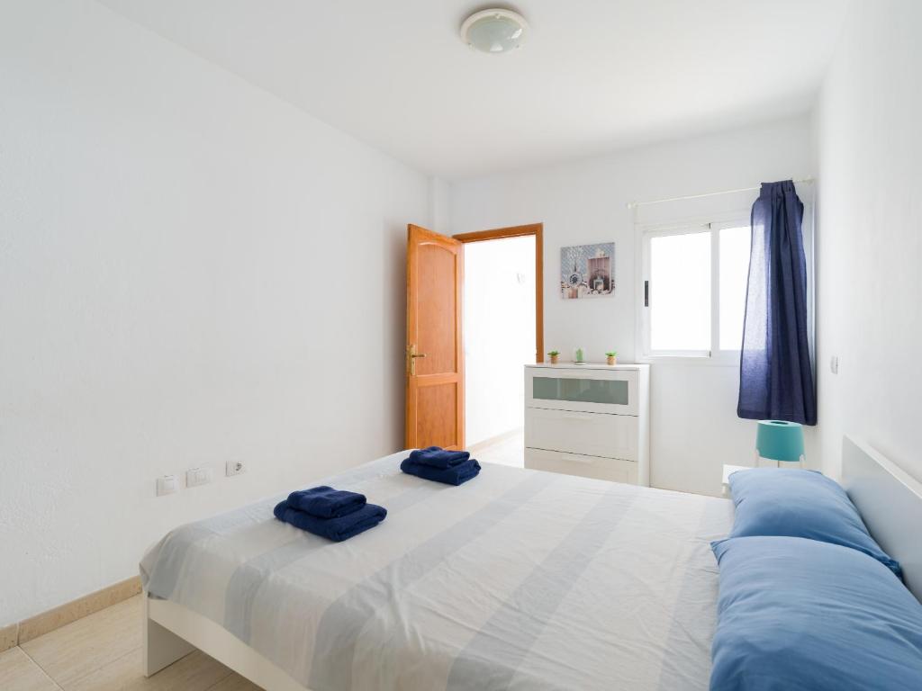 ein Schlafzimmer mit einem Bett mit zwei blauen Handtüchern darauf in der Unterkunft Apartamento Pura vida con WIFI Playas y compras in Vecindario