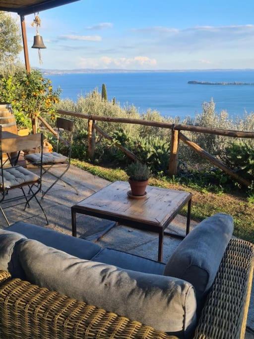 un divano e un tavolo su un patio con vista sull'oceano di Chalet Montecucco with lake view and jacuzzi a Gardone Riviera