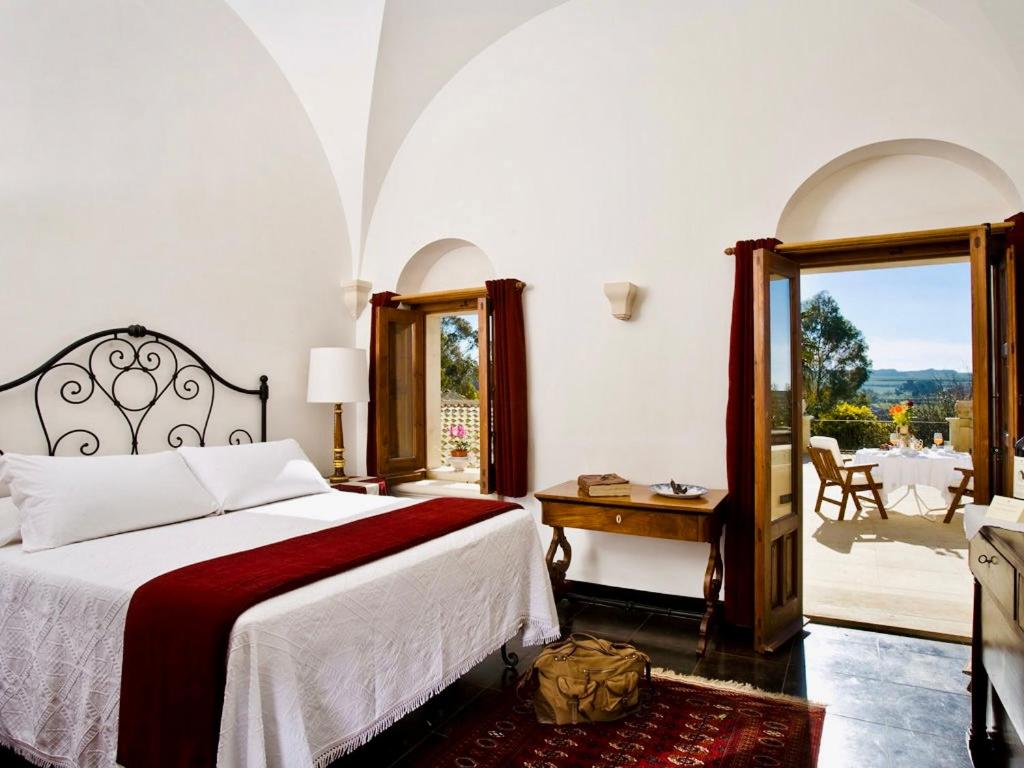 a bedroom with a bed and a view of a patio at Eremo Della Giubiliana in Ragusa