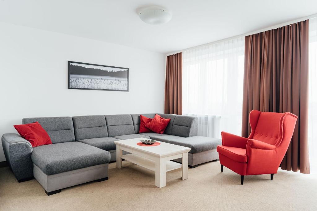 a living room with a couch and two red chairs at Hotel Logos in Warsaw