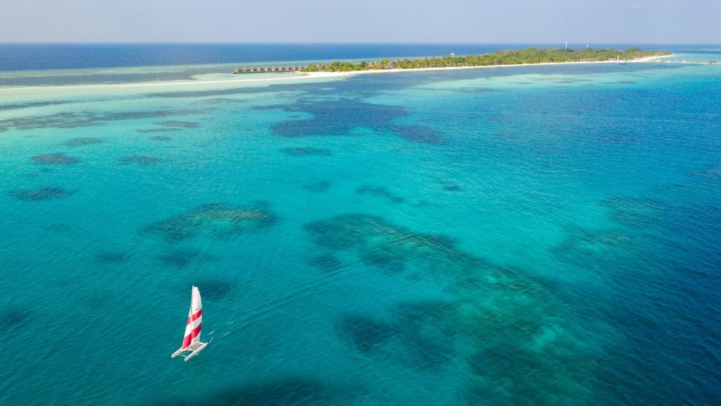a sail boat in the ocean with a small island at Kuredu Island Resort & Spa in Kuredu