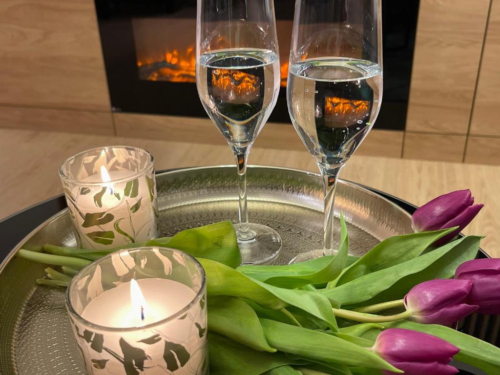 - deux verres de vin et de fleurs sur un plateau avec des bougies dans l'établissement Apartament nad jeziorem Długim Leśna # 32, à Olsztyn