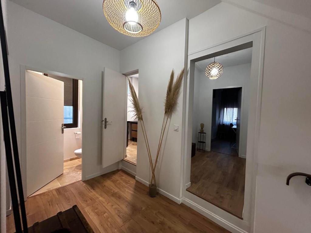 einen Flur mit weißen Wänden und einem großen Spiegel in der Unterkunft Le Paisiblement Vôtre 3 Ch, Terrasse, Clim, Park in Montauban