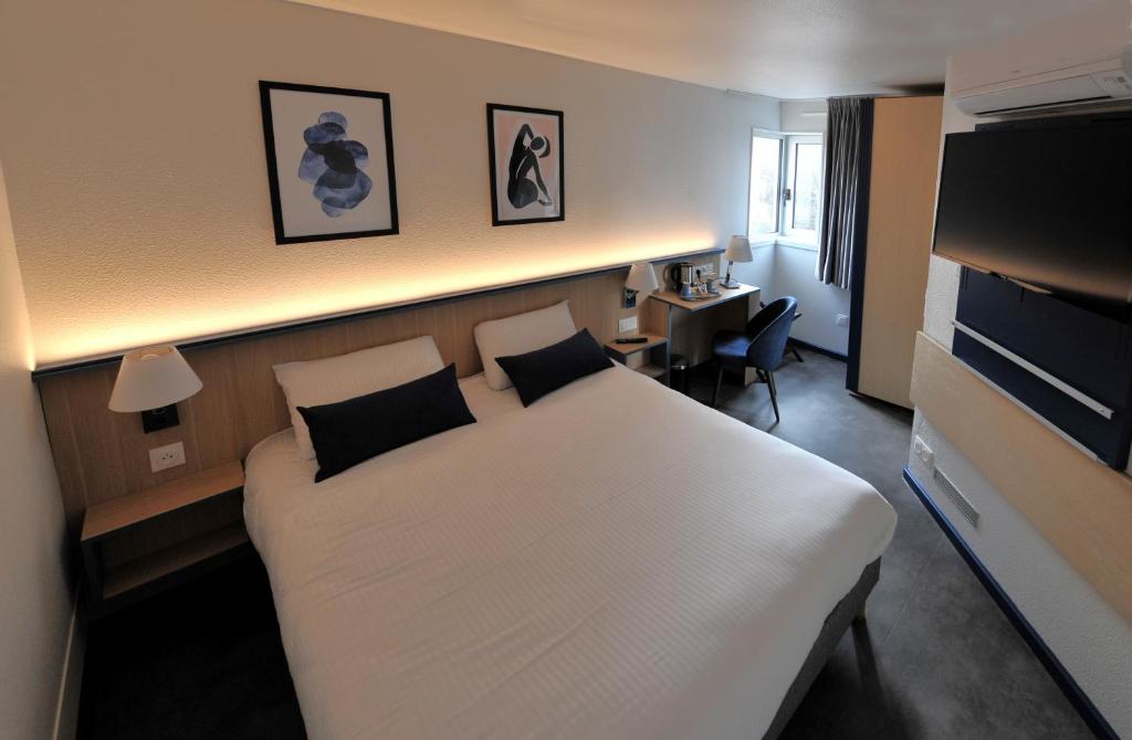 a hotel room with a white bed and a desk at Kyriad Villefranche Sur Saone in Villefranche-sur-Saône