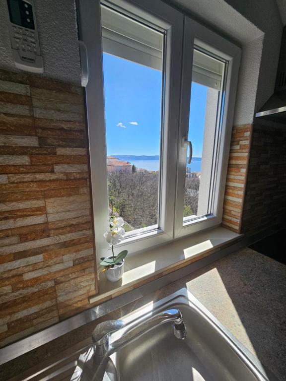 a bathroom with two windows and a sink with a view at Apartments Lujić in Crikvenica