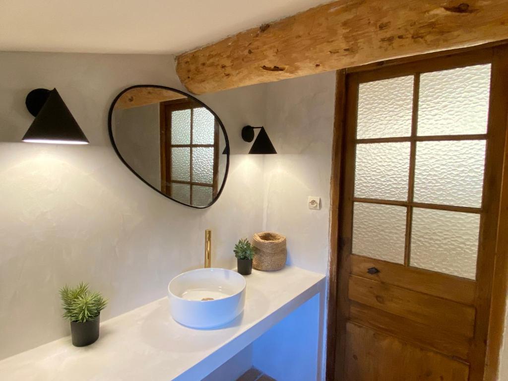 La salle de bains est pourvue d'un lavabo et d'un miroir. dans l'établissement Authentique Mazet et sa fontaine en Provence, à Fontvieille