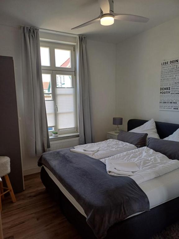 a bedroom with a large bed with a ceiling fan at Apartmenthaus Alte Börse in Carolinensiel