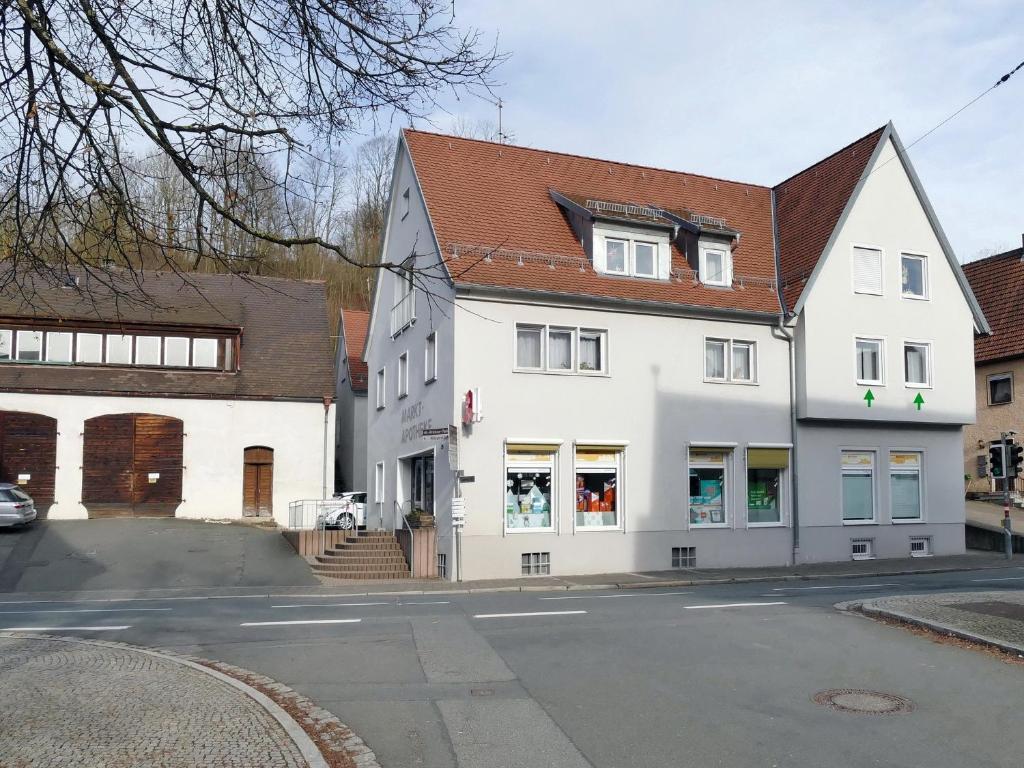 un edificio bianco con tetto marrone su una strada di Ihre Fewo mit Kunst und Design mitten in Heiligenstadt a Heiligenstadt in Oberfranken