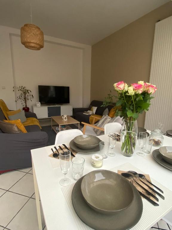 a living room with a table with plates and flowers on it at La grande Amiénoise de 7 chambres, quartier calme et résidentiel in Amiens