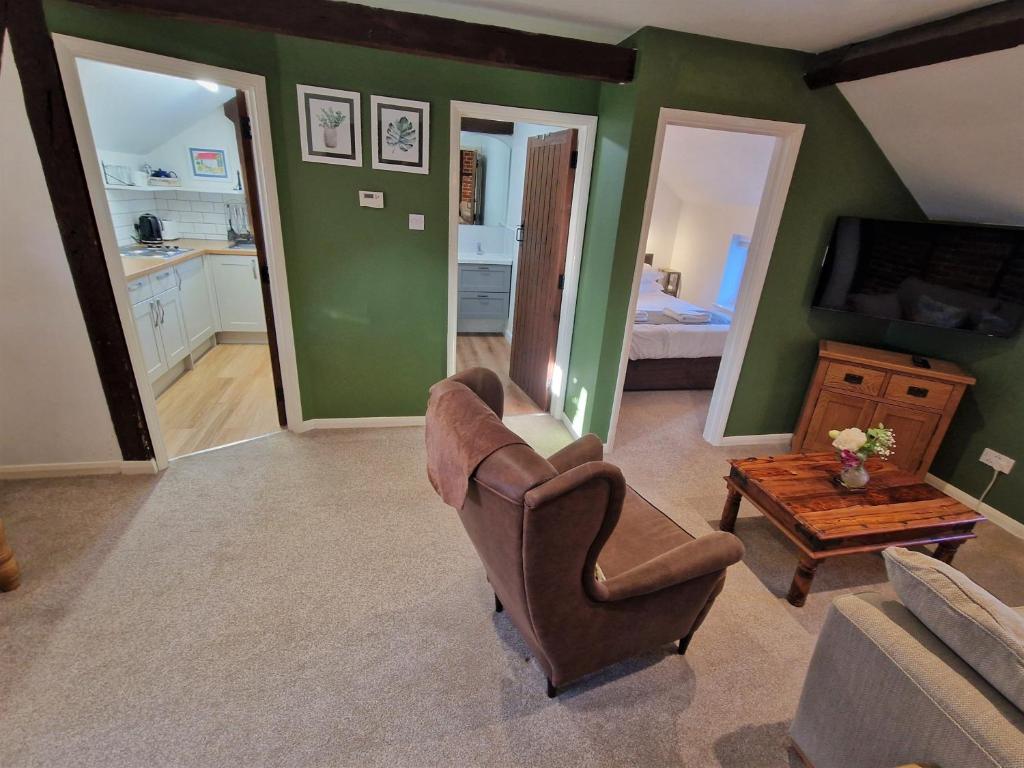 a living room with a chair and a couch and a television at The Hayloft in Ivinghoe