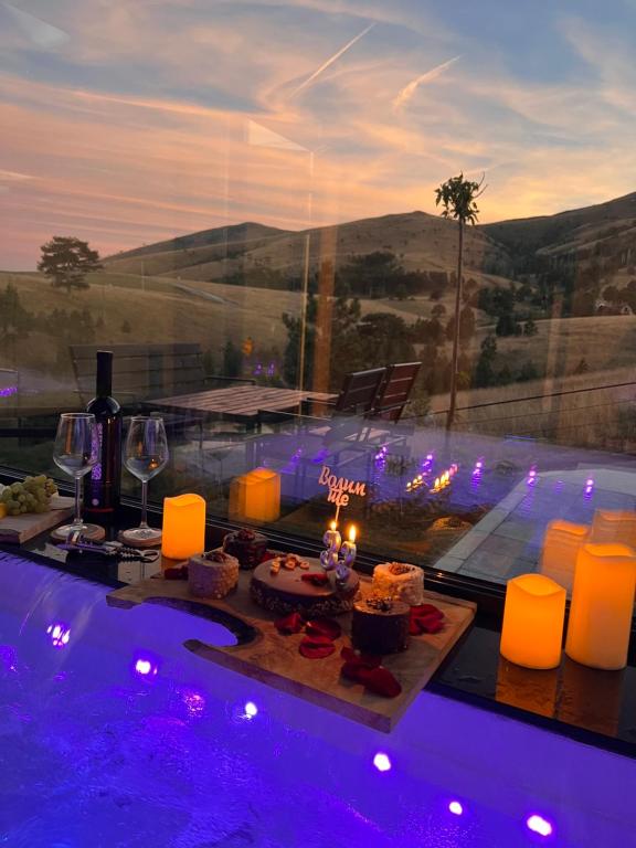 uma mesa com velas e copos de vinho ao lado de uma piscina em Zlatibor Wild em Zlatibor