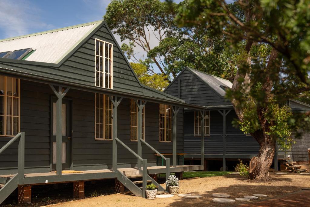 a black house with a tree in front of it at Shell House The South Coast Sandcastles in Huskisson in Huskisson