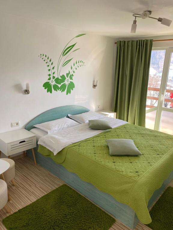 ein Schlafzimmer mit einem großen Bett und einer grünen Decke in der Unterkunft Casa Nicole in Moieciu de Jos