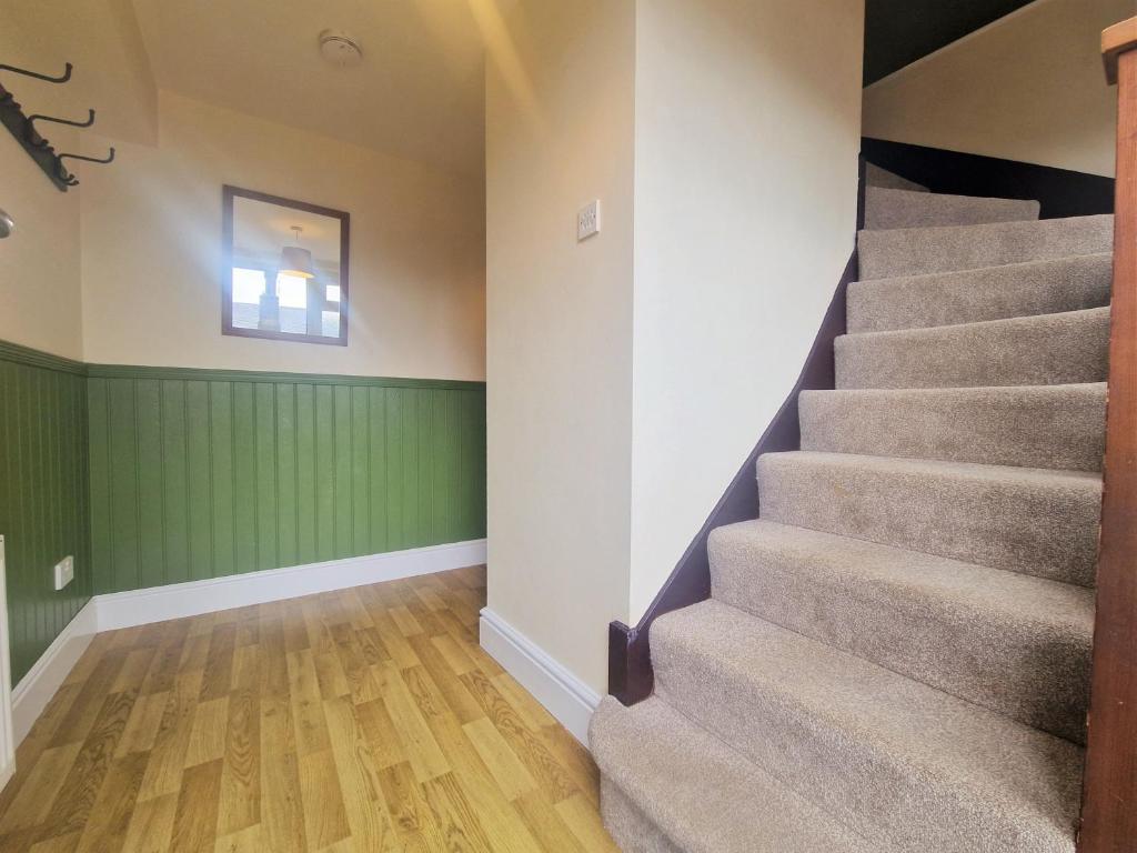 uma escada num quarto com paredes verdes e pisos em madeira em The Granary em Leighton Buzzard