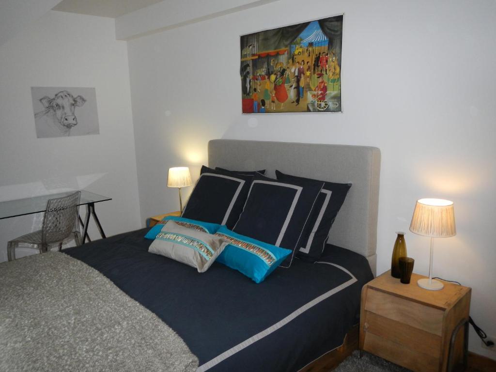 una camera da letto con letto con lenzuola e cuscini blu di L'appartement du Manoir a Gauciel