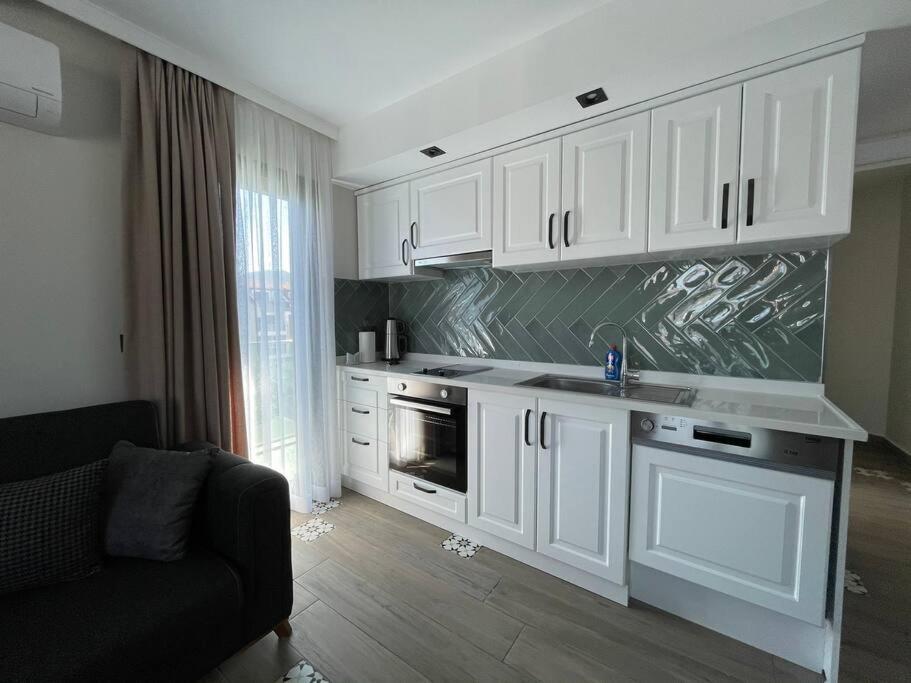een keuken met witte kasten en een bank in een kamer bij Zehra Suites Boutique Apartment#6, 300 meters from the sea in Marmaris
