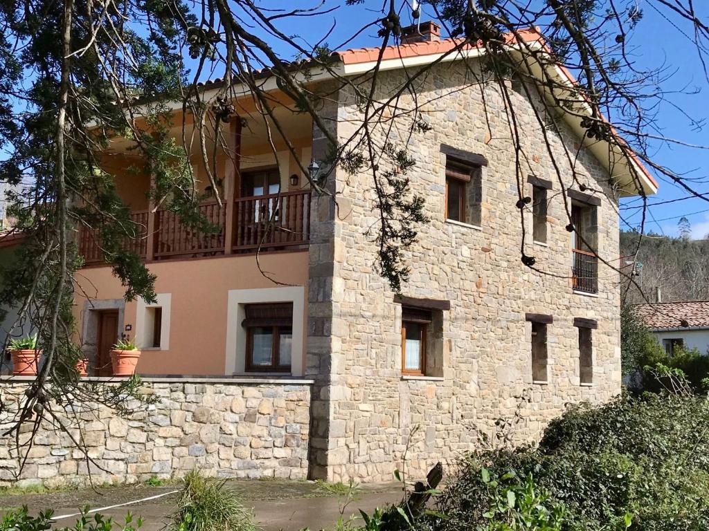 ein Steingebäude mit Balkon darüber in der Unterkunft La Xana del Profundu in Villaviciosa
