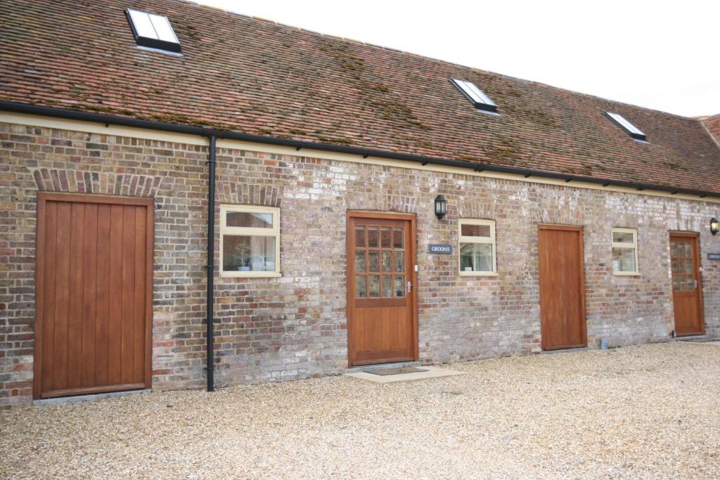 un edificio de ladrillo con puertas y ventanas de madera en Grooms Cottage en Leighton Buzzard